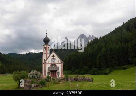 21.06.2019, St. Magdalena, Villnoess, Funes, Trentino, Südtirol, Italien, Europa - Kirche St. Johannes in Ranui im Naturpark Villnoesstal mit Bergen der Doldenberge der Puez-Geisler-Gruppe. [Automatisierte Übersetzung] Stockfoto