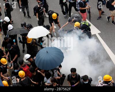 Demonstranten löschen Tränengasbombe, die von der Polizei im Yuen Long District in Hongkong gezündet wurde. Der Polizei wurde vorgeworfen, die Bürger bewusst nicht vor dem Angriff auf unschuldige Zugpassagiere in Yuen Long am 21. Juli 2019 geschützt zu haben. Stockfoto