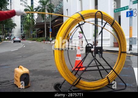 15.04.2018, Singapur, Republik Singapur, Asien - EIN Arbeiter legt Kabel auf eine Straße im Geschäftsviertel. [Automatisierte Übersetzung] Stockfoto