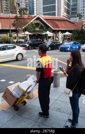 29.03.2019, Singapur, Republik Singapur, Asien - EIN Paketzusteller von DHL wartet an einer Ampel im Geschäftsviertel. [Automatisierte Übersetzung] Stockfoto