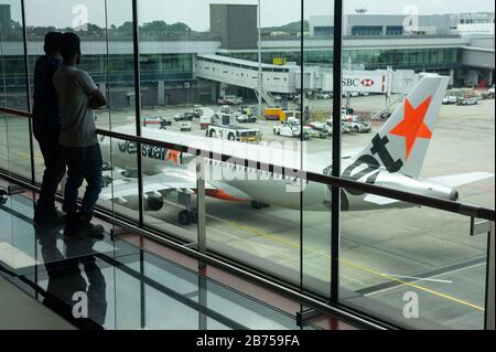 01.03.2019, Singapur, Republik Singapur, Asien - Besucher sehen von der Besuchertribüne im Terminal 1 des Flughafens Changi auf einen Jetstar Airbus A320 herab. [Automatisierte Übersetzung] Stockfoto