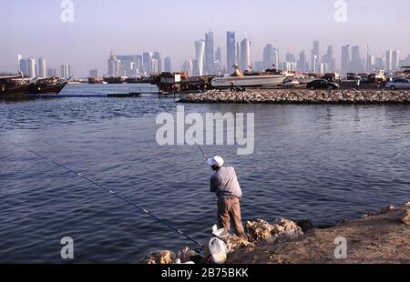 13.09.2010, Doha, Katar (Katar) - EIN Mann fischt auf der Promenade entlang der Al Corniche Street mit Blick auf die Skyline des Al Dafna Geschäftsviertels im Hintergrund. [Automatisierte Übersetzung] Stockfoto
