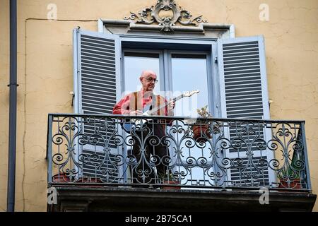 Turin, ITALIEN - 13. März 2020: Ein Mann spielt Gitarre vom Balkon seines Hauses in der Nachbarschaft von San Salvario während eines in ganz Italien gestarteten Blitzmobs, um Menschen zusammenzubringen. Die italienische Regierung hat beispiellose Einschränkungen auferlegt, um die Ausbreitung des COVID-19-Coronavirus-Ausbruchs zu stoppen, und andere Maßnahmen, die die Bewegungen der Menschen nur für die Arbeit, für den Kauf wesentlicher Waren und aus gesundheitlichen Gründen erlaubt sind. (Foto von Nicolò Campo/Sipa USA) Stockfoto