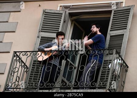 Turin, ITALIEN - 13. März 2020: Zwei Jungs spielen Gitarre und Flöte vom Balkon ihres Wohnhauses in der Nachbarschaft von San Salvario während eines in ganz Italien gestarteten Blitzmobs, um die Menschen zusammenzubringen. Die italienische Regierung hat beispiellose Einschränkungen auferlegt, um die Ausbreitung des COVID-19-Coronavirus-Ausbruchs zu stoppen, und andere Maßnahmen, die die Bewegungen der Menschen nur für die Arbeit, für den Kauf wesentlicher Waren und aus gesundheitlichen Gründen erlaubt sind. (Foto von Nicolò Campo/Sipa USA) Stockfoto