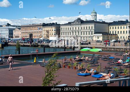 23.06.2018 - Helsinki, Finnland, Europa - Besucher sonnen sich auf der Sonnenterasse des Allas Sea Pool mit Blick auf den Hafen und den Marktplatz. Im Hintergrund stehen der Präsidentenpalast und die Kathedrale von Helsinki. [Automatisierte Übersetzung] Stockfoto