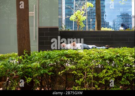 18.04.2018, Singapur, Republik Singapur, Asien - EIN Mann schläft hinter einer Hecke im Geschäftsviertel der Innenstadt von Singapur. [Automatisierte Übersetzung] Stockfoto