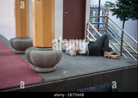 22.03.2018, Singapur, Republik Singapur, Asien - EIN Mann nimmt ein Nickerchen auf dem Boden eines Podiums am Crete Ayer Square im Singapur-Chinatown-Viertel. [Automatisierte Übersetzung] Stockfoto