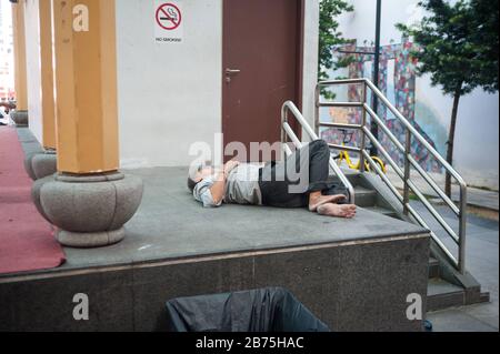 22.03.2018, Singapur, Republik Singapur, Asien - EIN Mann nimmt ein Nickerchen auf dem Boden eines Podiums am Crete Ayer Square im Singapur-Chinatown-Viertel. [Automatisierte Übersetzung] Stockfoto