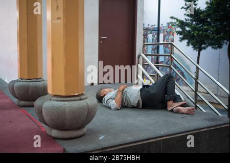 22.03.2018, Singapur, Republik Singapur, Asien - EIN Mann nimmt ein Nickerchen auf dem Boden eines Podiums am Crete Ayer Square im Singapur-Chinatown-Viertel. [Automatisierte Übersetzung] Stockfoto