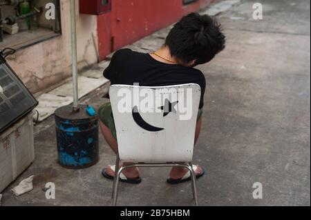 31.03.2018, Singapur, Republik Singapur, Asien - EIN junger Mann sitzt auf einem Stuhl im Chinatown-Distrikt von Singapur und nimmt einen Nickerchen. [Automatisierte Übersetzung] Stockfoto