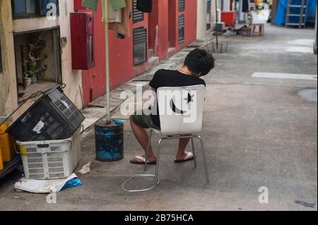 31.03.2018, Singapur, Republik Singapur, Asien - EIN junger Mann sitzt auf einem Stuhl im Chinatown-Distrikt von Singapur und nimmt einen Nickerchen. [Automatisierte Übersetzung] Stockfoto