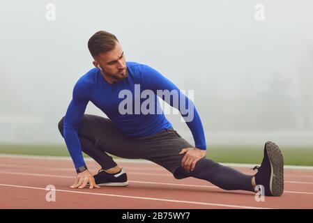 Ein Mann wärmt sich vor dem Training im Stadion auf Stockfoto