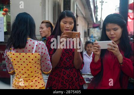 28.01.2017, Yangon, Yangon Region, Republik der Union von Myanmar, Asien - junge Frauen sind während der chinesischen Neujahrsfeier auf ihren Smartphones gebannt. [Automatisierte Übersetzung] Stockfoto