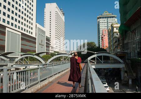 27.01.2017, Yangon, Yangon Region, Republik der Union von Myanmar, Asien - EIN buddhistischer Mönch steht auf einer Fußgängerbrücke und fotografiert das neue Gebäude am Sule Square im Zentrum von Yangon. [Automatisierte Übersetzung] Stockfoto