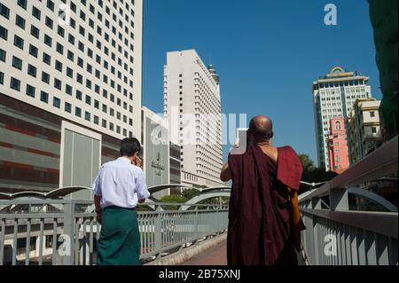 27.01.2017, Yangon, Yangon Region, Republik der Union von Myanmar, Asien - EIN buddhistischer Mönch steht auf einer Fußgängerbrücke und fotografiert das neue Gebäude am Sule Square im Zentrum von Yangon. [Automatisierte Übersetzung] Stockfoto