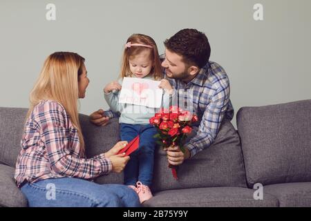 Glücklicher Muttertag. Tochter gibt Mutter eine Karte mit Herzblumen Geschenk Stockfoto