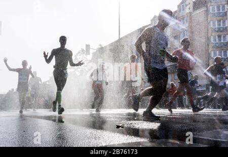 Die Teilnehmer des 43. Berlin-Marathons im Berliner Schöneberger Kreis werden mit einer Wasserdusche abgekühlt. 41.283 Läufer nahmen am Marathon Teil. [Automatisierte Übersetzung] Stockfoto