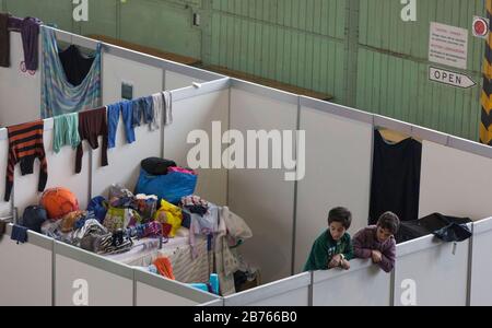 Kinder von Flüchtlingen blicken am 9. Dezember 2015 im ehemaligen Hangar des Flughafens Tempelhof über die Wand eines provisorischen Raumes in einer Notunterkunft für Flüchtlinge. Der Flughafen Tempelhof dient der Stadt Berlin als Notunterkunft für Flüchtlinge. [Automatisierte Übersetzung] Stockfoto