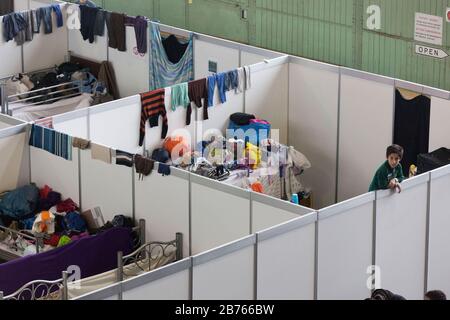 Kinder von Flüchtlingen blicken am 9. Dezember 2015 im ehemaligen Hangar des Flughafens Tempelhof über die Wand eines provisorischen Raumes in einer Notunterkunft für Flüchtlinge. Der Flughafen Tempelhof dient der Stadt Berlin als Notunterkunft für Flüchtlinge. [Automatisierte Übersetzung] Stockfoto