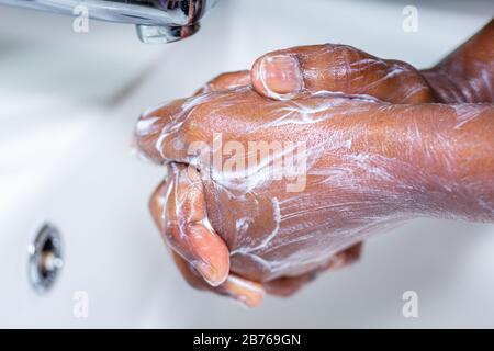 Nahaufnahme der schwarzen Afrikanerin, die die Hände mit Seife im Waschbecken waschen Stockfoto