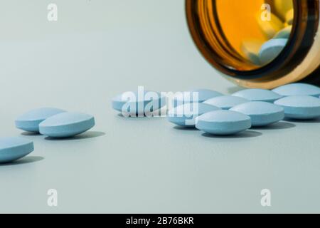 Nahaufnahme von verschütteten blauen Pillen über der grauen Oberfläche in niedriger Winkelperspektive Stockfoto