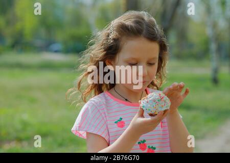 Schönes Mädchen im Park vor grünem Gras im Frühjahr mit Osterpanetton. osterpascha und Kulich. Sonniger Frühlingstag, fröhliche Familienvorbereitung Stockfoto