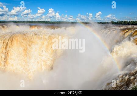 Blick auf einen Teil des Garganta del Diablo im Nationalpark Iguazú mit Regenbogen und bewölktem Himmel Stockfoto