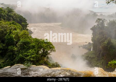 Ein Wasserfall von oben gesehen, ein Teil der Iguazu-Wasserfälle mit umgebender Natur in Argentinien mit Blick auf Bäume und Fluss mit Wassernebel Stockfoto