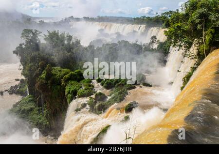 Ein Wasserfall von oben gesehen, ein Teil der Iguazu-Wasserfälle mit umgebender Natur in Argentinien mit Blick auf Bäume und Fluss mit Wassernebel und isla Stockfoto