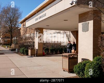 Oak Park, Illinois, USA. März 2020. Ein Polizist steht am Haupteingang der Oak Park River Forest High School unter Beobachtung. Die Schule hat als Vorsichtsmaßnahme gegen Coronavirus/COVID-19 geschlossen Stockfoto