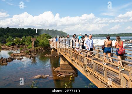 Geschäftige Spazierwege mit Touristen als Folge der Karnevalsferien in Foz do Iguaçu Brasilien und Argentinien. Holzbrücke über Wasser im Iguazu-Nationalpark. Stockfoto