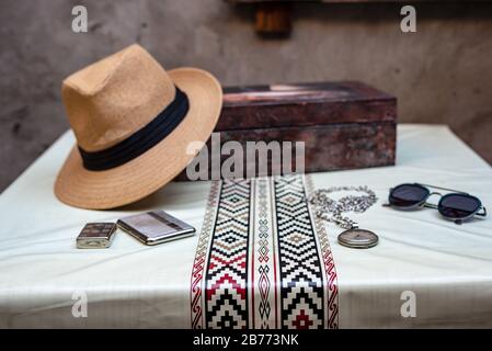Hut, leichter, Zigarrenetui, Brille, alte Uhr und eine Holzkiste auf einem weißen Tisch mit pampa Wache Stockfoto