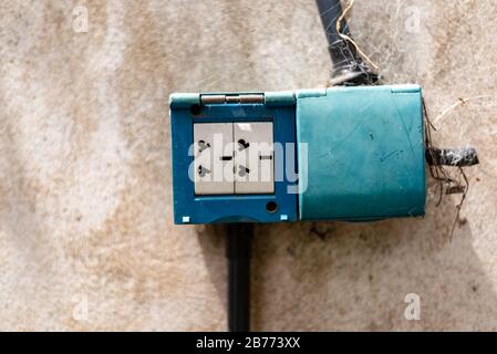 Alter Netzstecker an einer Betonwand mit einigen Spinnweben Stockfoto
