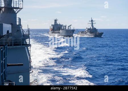 200310-N-KW492-1105 PHILIPPINISCHES MEER (MÄRZ 10, 2020) Der Lenkflugkörperzerstörer der Arleigh-Burke-Klasse, USS Mustin (DDG 89), rechts, erhält während eines Nachschubs auf See mit dem Flottennachschub Oiler USNS Pecos (T-AO 197) Treibstoff und Ladung, während der geführte Panzerkreuzer der Ticonderoga-Klasse USS Shiloh (CG 67) wegzieht. Shiloh wird im 7. Flottengebiet der Vereinigten Staaten zur Unterstützung von Sicherheit und Stabilität in der Region Indopazifik eingesetzt. (USA Navy-Foto von Mass Communication Specialist 2. Klasse Ryre Arciaga) Stockfoto