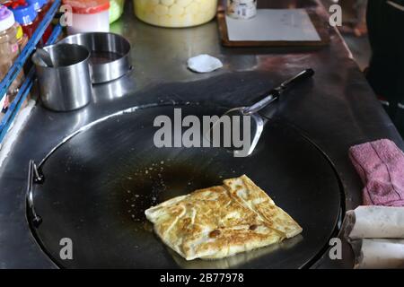 Roti Eier gebraten (thailändisches Wort) in einer Nachtmarktstraße, indische Küche, Chapati Fladenbrot, Roti Canai, dal, Curry, Teh Tarik oder gezupft Tee, acar. Berühmt in Stockfoto