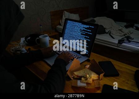 Späte Nacht Männer Computer Hacking Code in unordentliche Hotelzimmer Dunkle Internet Cyberkriminalität Sicherheitsverstöße Informationen handeln Kreditkartenbetrug Identitätsdiebstahl. Stockfoto