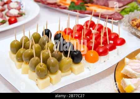 Nahaufnahme kleiner, auf einer Platte angeordneter Canapes über hellem Hintergrund - selektiver Fokus Stockfoto