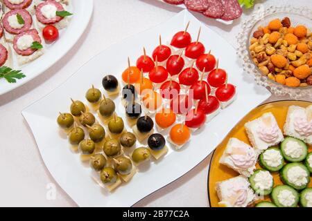 Nahaufnahme kleiner, auf einer Platte angeordneter Canapes über hellem Hintergrund - selektiver Fokus Stockfoto