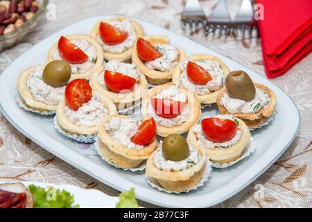 Nahaufnahme kleiner, auf einer Platte angeordneter Canapes über hellem Hintergrund - selektiver Fokus Stockfoto