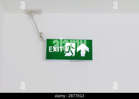 Schilder für den Notausgang, grün für die Feuerlöscheinheit, Pfeilschilder an der weißen Wand, Hinweisschilder für den Notfall, grüne Leuchtkastenschilder, erste Sicherheitsschilder Stockfoto