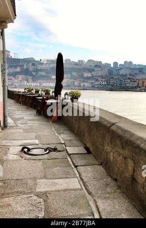 Leere Terrasse an der Bar am Ufer des Flusses Douro in Oporto in einem bewölkten Wintertag Stockfoto