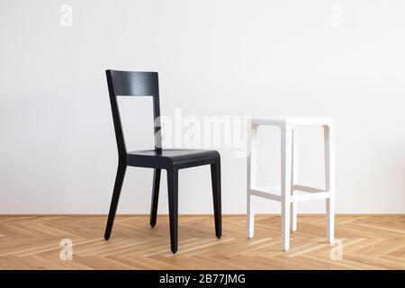 Moderner, vereinfachter, schwarz-weißer Stuhl auf einem Holzflor vor weißem Hintergrund Stockfoto