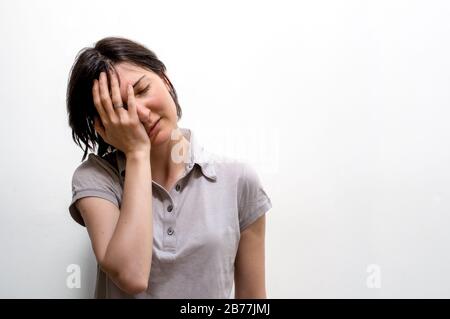 Porträt einer jungen brünettierten Frau, die ihr Gesicht mit der Hand schließt. Schlechte psychische Gesundheit, negative Emotionen Konzept. Stockfoto