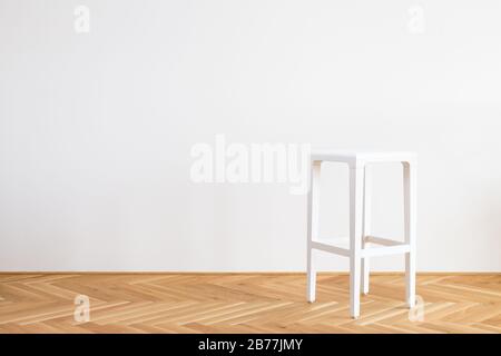 Moderner, vereinfachter weißer Stuhl auf einem Holzflor vor weißem Hintergrund Stockfoto