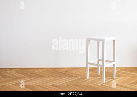 Moderner, vereinfachter weißer Stuhl auf einem Holzflor vor weißem Hintergrund Stockfoto
