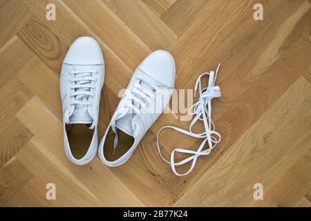 Trendige Sneaker aus weißem Grundleder auf Holzboden Stockfoto