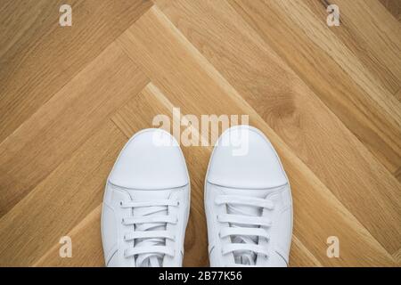 Trendige Sneaker aus weißem Grundleder auf Holzboden Stockfoto