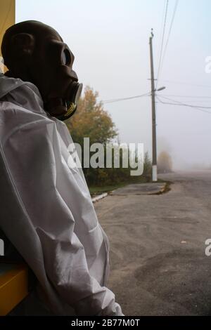 Schaufensterpuppe mit Schutzanzug und alter sowjetischen Gasmaske, die an einem nebligen Morgen in der Ausschlusszone von Tschernobyl in der Ukraine in einem Souvenirladen zu verkaufen ist. Stockfoto