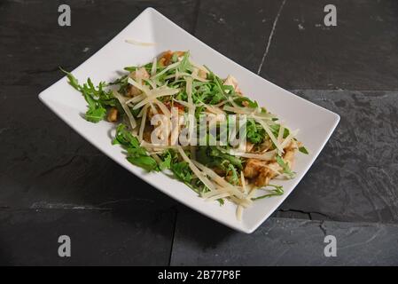 Hühnerstäbchen mit Käsestäbchen und Raketensalat auf weißem Gericht - horizontaler Studioschuss Stockfoto