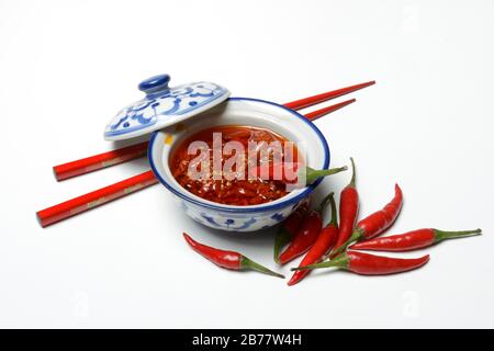 Zerkleinerte Chilischoten in Öl in der Schale und rote Essstäbchen, Deutschland Stockfoto